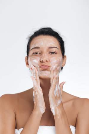 Playful Woman Making a Funny Face While Washing Her Faceの写真素材