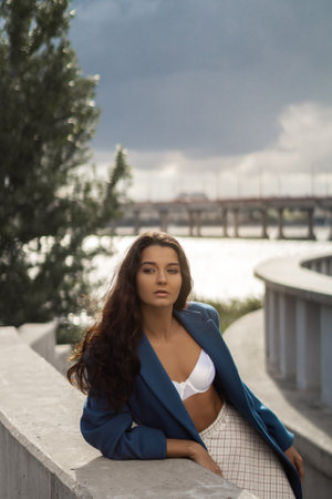 Confident Brunette Woman in Stylish Blazer Posing Outdoors at Sunsetの写真素材