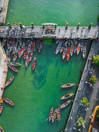 Aerial View of Colorful Wooden Boats Docked Along River Bridge in Hoi An