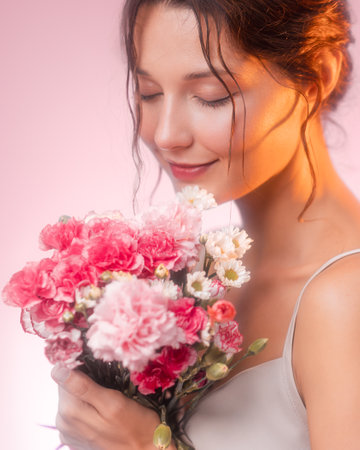 Smiling Woman Holding Fresh Flower Bouquet in Soft Pink Studio Lightの写真素材