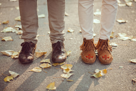 Couples Feet On Autumn Leaf-Covered Path In Casual Footwearの写真素材