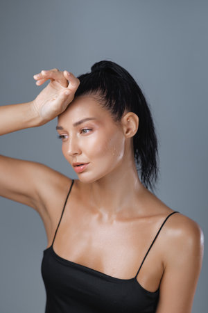 Sweaty Fit Woman Wiping Forehead After Workout in Studio With Wet Lookの写真素材