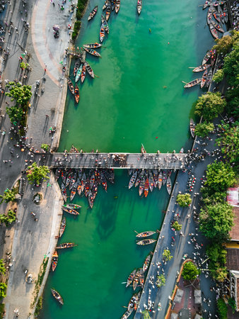 Top-Down Drone Image of Hoi An Boats Moored by Bridge Over Green Riverの写真素材