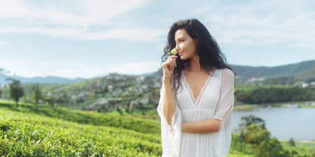 Elegant Woman in Tea Field Enjoying Aroma of Fresh Tea Flower in Sri Lanka