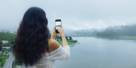 Woman Taking Photo of Misty Lake Gregory in Nuwara Eliya, Sri Lankaの写真素材