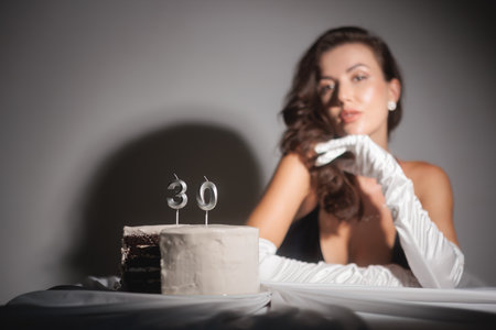 Elegant Woman in Satin Gloves Posing with 30th Birthday Cake Celebrationの写真素材