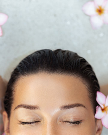 Close-Up Of Womans Face With Flowers And Closed Eyes In Spa Waterの写真素材