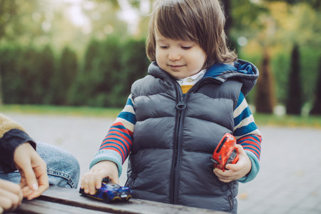 Young Boy Playing With Toy Cars Outdoors On A Cool Autumn Dayの写真素材