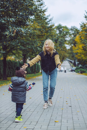 Mother Welcoming Her Son with Open Arms in Autumn Park