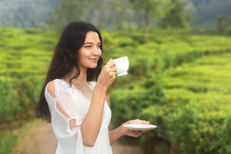 Beautiful Woman Enjoying Fresh Tea in Green Hills of Ceylon Plantationの写真素材