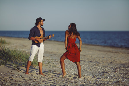 Young Couple Enjoying Music and Dancing Together on a Sandy Beachの写真素材