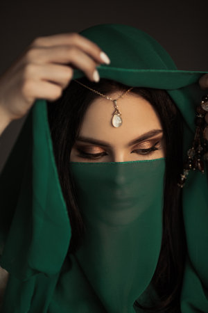 Veiled Woman With Closed Eyes Holding Green Hijab and Spiritual Beadsの写真素材