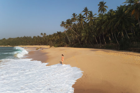 Woman Standing By Ocean Waves On Silent Beach Tangalle Sri Lankaの写真素材