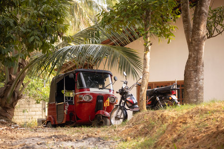 Red Tuk Tuk And Motorbikes Parked Near House Under Tropical Palm Trees