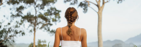 Woman Meditating Outdoors Facing Nature In Peaceful Forest Settingの写真素材