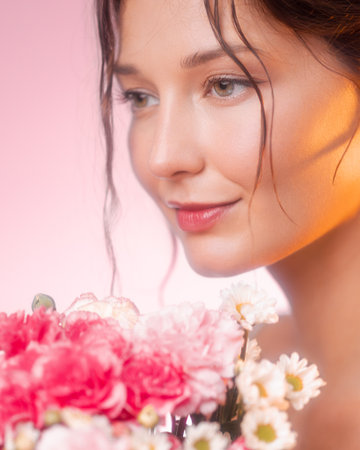 Beautiful Woman Gazing at Pink and White Flowers in Soft Lightの写真素材