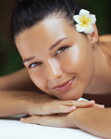 Beautiful Young Woman With Flower In Hair Resting At Spa Wellness Retreatの写真素材
