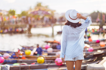 Woman In White Outfit Holding Hat In Hoi An Vietnam With Lantern Boatsの写真素材