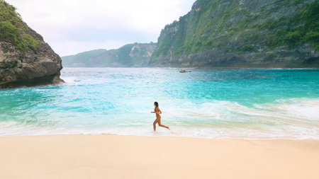 Kelingking Beach Nusa Penida Woman Running By Secluded Turquoise Coveの写真素材