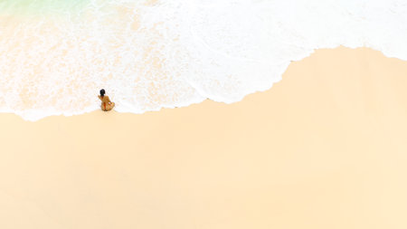 Drone Shot Of Woman Sitting Alone On Kelingking Beach Nusa Penidaの写真素材