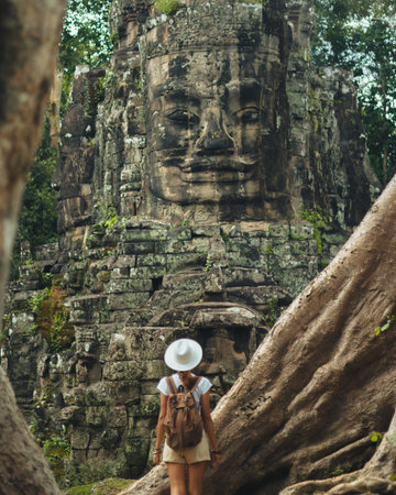 Backpacker Facing Bayon Face Tower Through Roots, Angkor Thom Cambodiaの写真素材