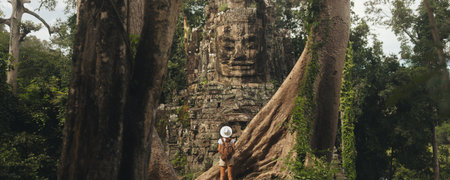Solo Backpacker at Bayon Victory Gate, Framed by Giant Jungle Rootsの写真素材