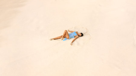 Aerial View Of Woman In Blue Dress Relaxing On Minimal Sand Beachの写真素材