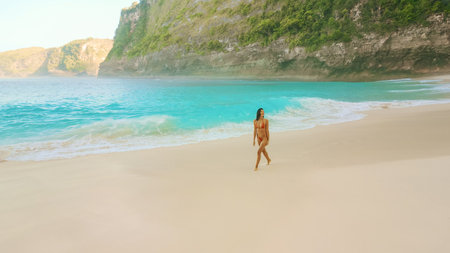 Woman Walking On Turquoise Kelingking Beach In Bali At Golden Hourの写真素材