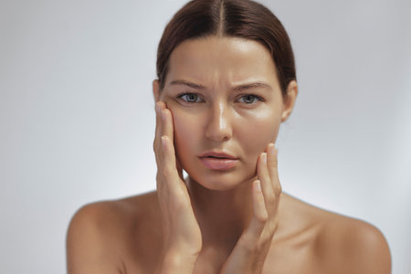 Dissatisfied Woman Touching Face With Concerned Look In Studio Beauty Portraitの写真素材