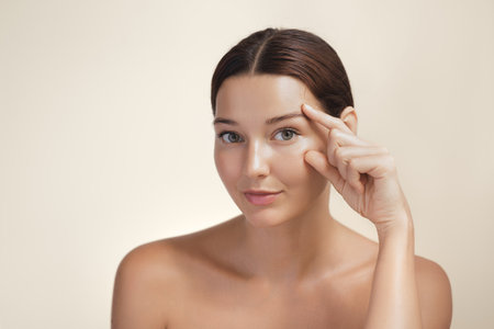 Natural Beauty Woman Pointing At Eye Area For Skincare Conceptの写真素材