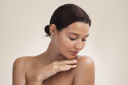 Close-Up Of Woman With Glowing Skin Touching Shoulder In Skincare Conceptの写真素材