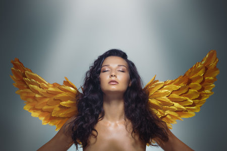 Serene Angel Woman With Glowing Skin And Golden Wings In Studio Fantasyの写真素材
