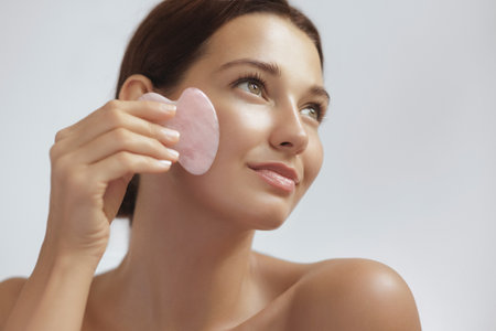 Beautiful Woman Using Gua Sha Tool On Face For Skincare And Facial Wellnessの写真素材