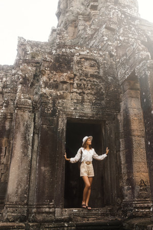 Young Tourist Exploring Bayon Temple Ancient Stone Faces In Cambodiaの写真素材