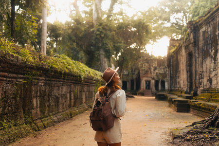 Female Traveler Exploring Ancient Angkor Temple Passage At Sunrise Lightの写真素材