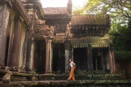 Traveler Woman Exploring Ancient Angkor Wat Temple With Monkeys In Cambodiaの写真素材