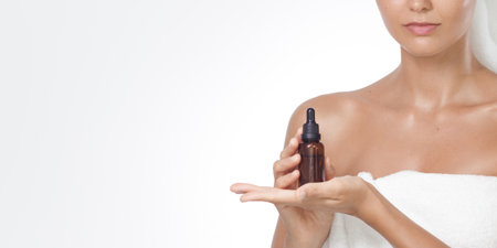 Minimal Spa Product Display With Woman Holding Amber Face Serum Bottleの写真素材