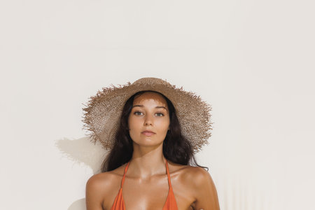 Stylish Woman In Straw Hat And Orange Bikini Under Bright Sunlightの写真素材