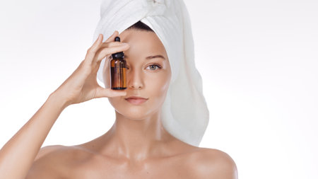 Clean Beauty Concept: Towel-Wrapped Woman With Amber Dropper Face Serumの写真素材