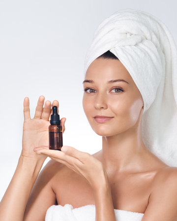 Spa Skincare Concept Woman Holding Amber Serum Bottle In White Towelの写真素材