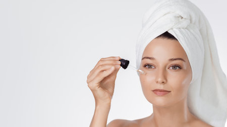 Skincare Serum Application: Woman With Towel Turban On White Backgroundの写真素材