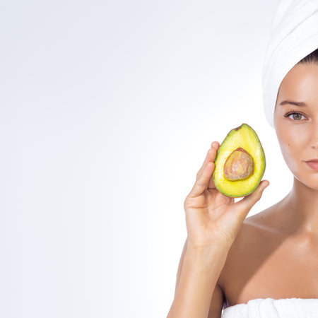 Title Serene Woman Pressing Avocado to Face in Spa Towel Relaxationの写真素材