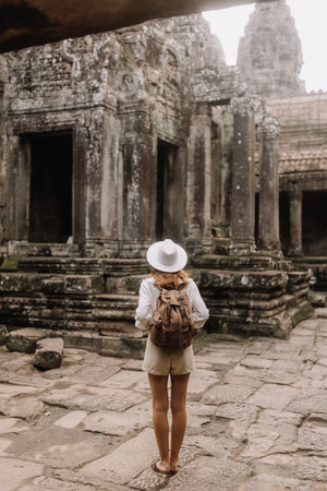 Back View Of Woman Tourist Exploring Ancient Temple In Cambodiaの写真素材