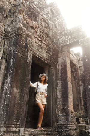 Young Woman Standing At Bayon Temple, Cambodia, Exploring Ancient Ruinsの写真素材