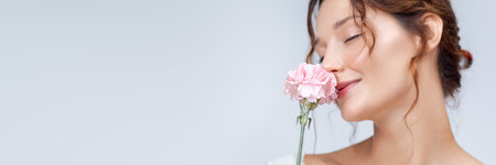 Woman With Closed Eyes Smiling While Smelling Pink Carnation Flowerの写真素材