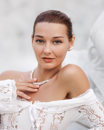 Close-Up Portrait of Elegant Woman in White Lace and Pearl Jewelryの写真素材