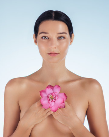 Serene Woman Posing with Pink Lotus Flower for Natural Beauty and Spa Conceptの写真素材
