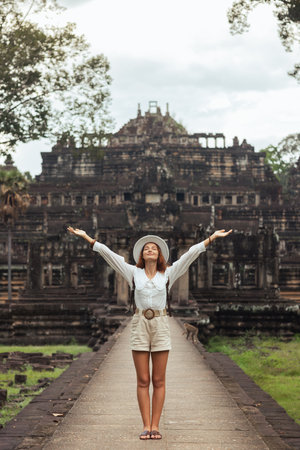 Joyful Woman with Arms Raised at Baphuon Temple in Angkor Thomの写真素材