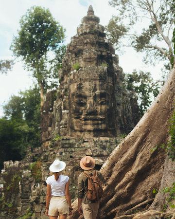 Travel Couple Visiting Iconic Bayon Temple Stone Face In Cambodia Jungleの写真素材