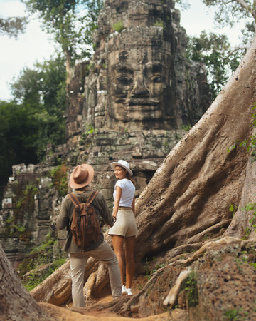 Young Couple Holding Hands Exploring Bayon Temple Gate in Angkor Watの写真素材